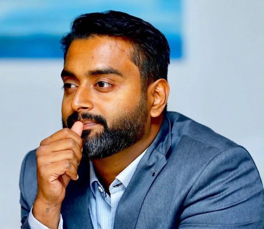 Prabeesh Chambeth in a grey suit, listening in a meeting