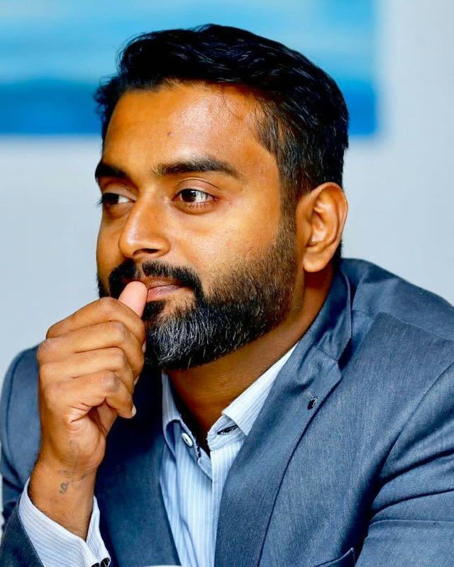Prabeesh Chambeth in a grey suit, listening in a meeting